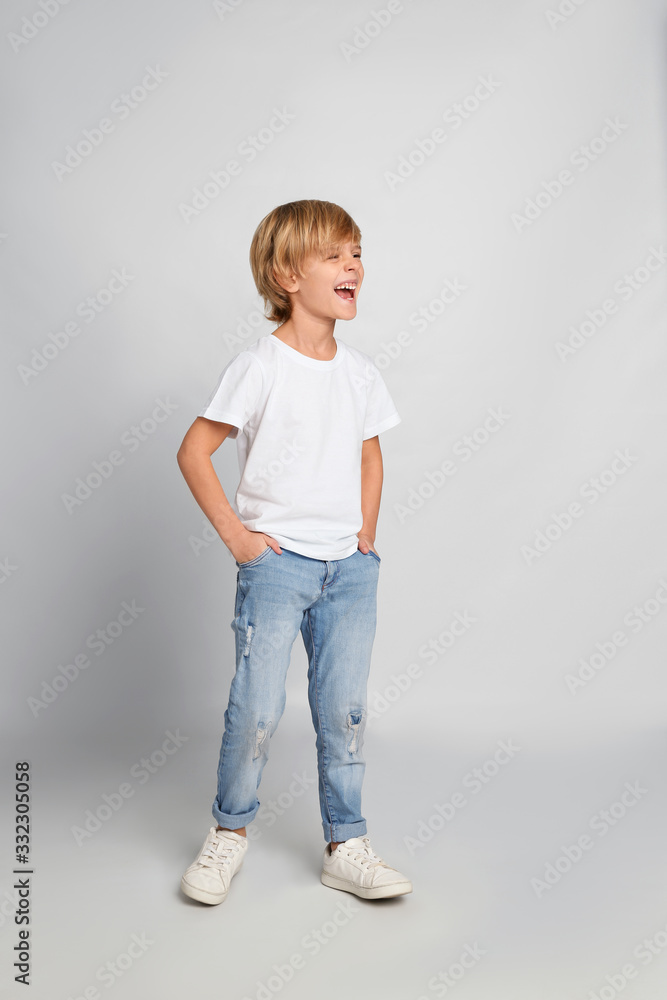 Happy little boy in casual outfit on light grey background