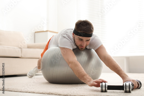 Lazy young man with sport equipment at home