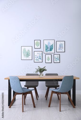 Stylish room interior with modern table  chairs and paintings of tropical leaves. Idea for design