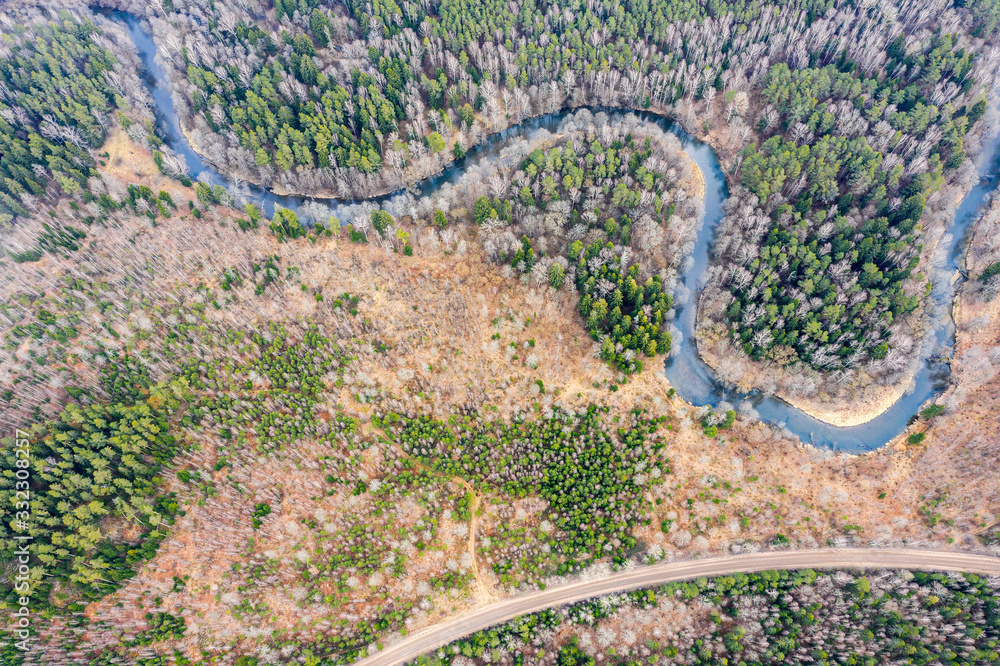 spring landscape over forest from a bird's eye view. small winding river near rural dirt road