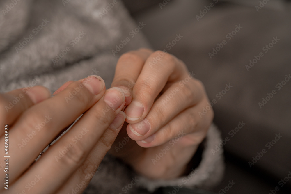 The woman is cutting her nails with small scissors by herself in close up photo