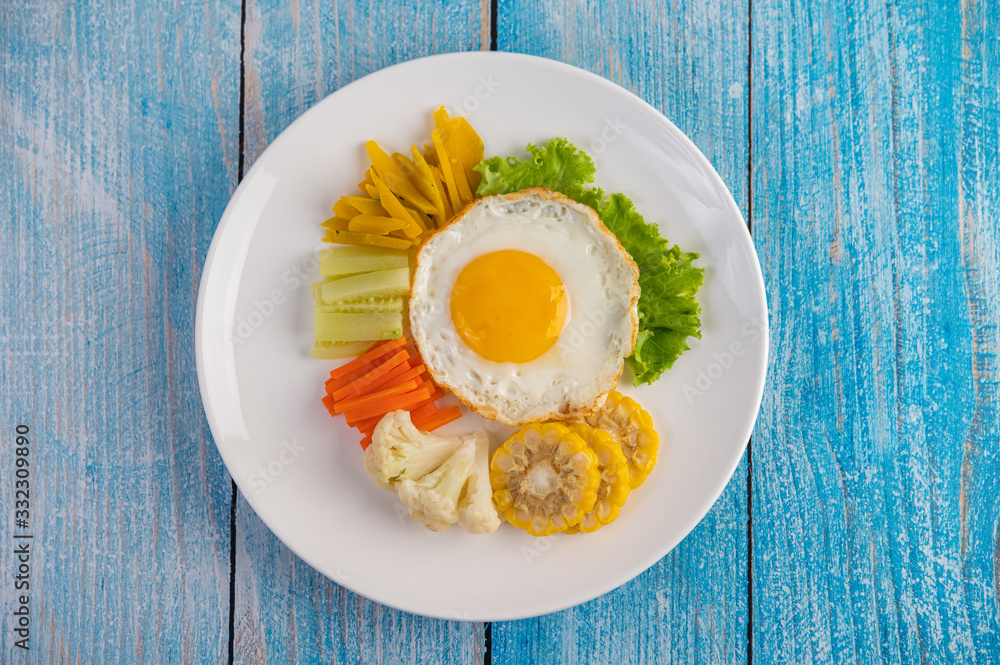 American breakfast on a white background with fried egg, salad, pumpkin, cucumber, carrot, corn, cauliflower and tomato.