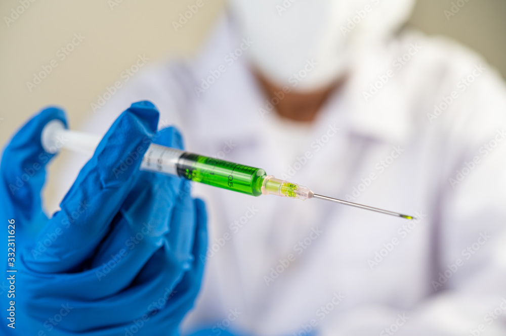 Scientists wearing masks and gloves Holding a syringe with a vaccine to prevent covid-19 Scientists wearing masks and gloves Holding a syringe with a vaccine to prevent covid-19