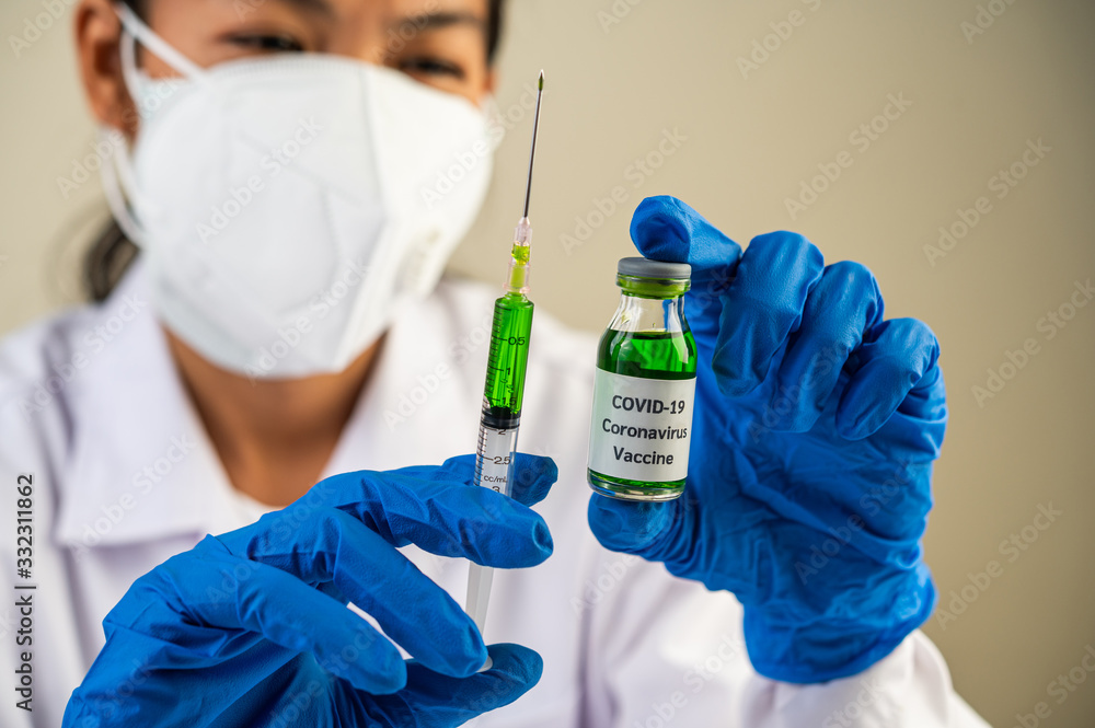 Scientists wearing masks and gloves Holding a syringe with a vaccine to prevent covid-19 Scientists wearing masks and gloves Holding a syringe with a vaccine to prevent covid-19
