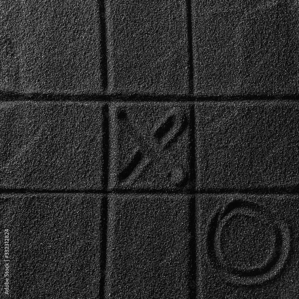Fototapeta premium Playing on the black sand beach. Drawing with finger. Cross-zero. Tic-tac-toe game.