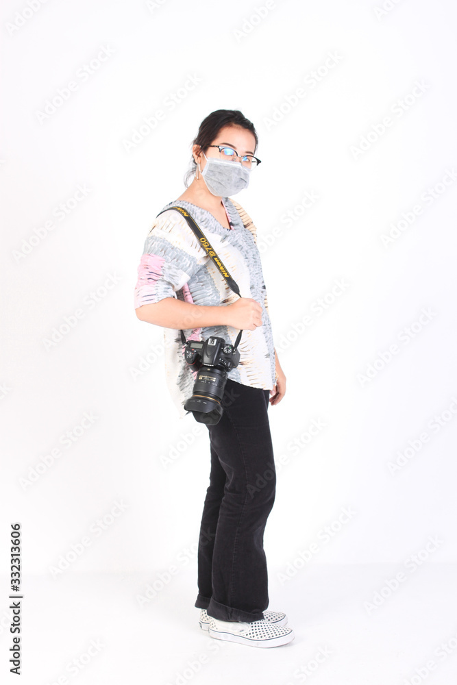 THAILAND - NOVEMBER 27, 2019 Photographer wearing face mask A gril holds in his hands a Nikon digital SLR camera against a white background. Camera Nikon D750. THAILAND - NOVEMBER 27, 2019 Photographer wearing face mask A gril holds in his hands a Nikon digital SLR camera against a white background. Camera Nikon D750.