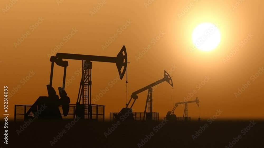 Oil pump jacks in the desert against sunset extracting fossil oil