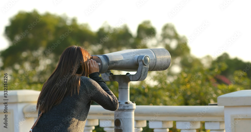 Woman tourist looking though the binocular at outdoor