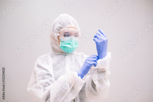 Young Nurse with disposable coverall wearing sterile gloves preparing take care of Pandemic 2019 Coronavirus 2019-nCoV.