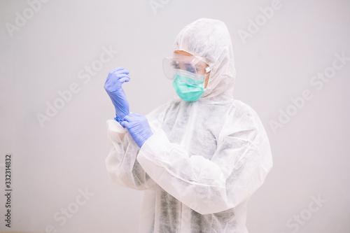 Young Nurse with disposable coverall wearing sterile gloves preparing take care of Pandemic 2019 Coronavirus 2019-nCoV.