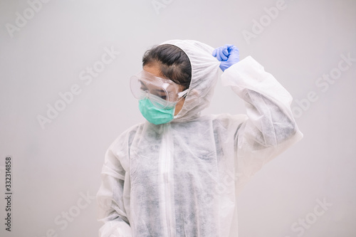 Tired Young Nurse take off disposable coverall with mask and safety googles after take care of Pandemic 2019 Coronavirus 2019-nCoV.