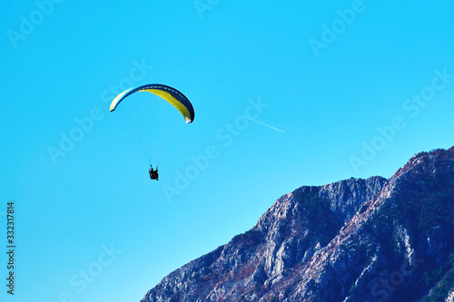 Paragliding above the mountains. Extreme sport. Parachute flying in the sky. Brave feeling