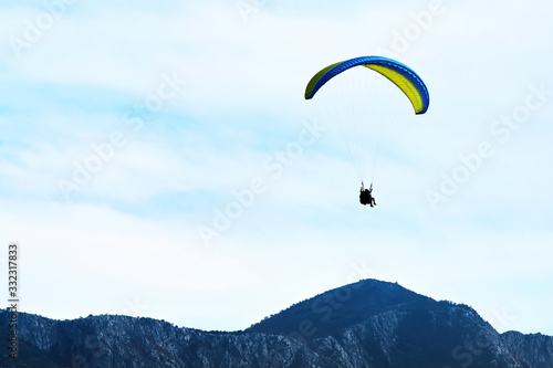 Skydiver flying above the mountains. Extreme sport. Parachute flying in the sky. Brave feeling