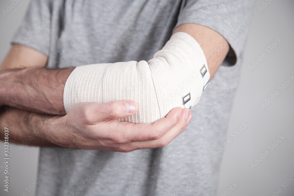 Man hand with elastic bandage on elbow.