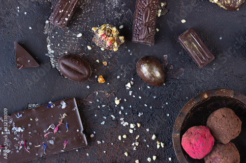 Assortment of sweet confectionery with chocolate candies and pralines on a dark brown stone background. 