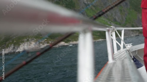 Fishing rod over side of aluminium boat rocking in the water with rugged landscape photo
