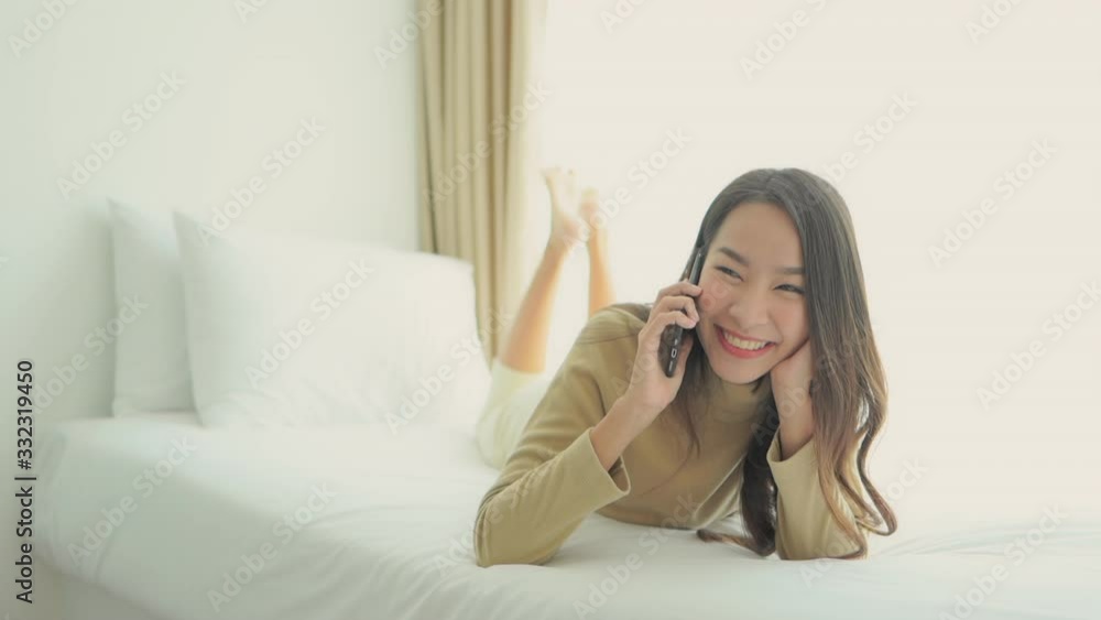 Asian woman speak on the phone and laugh, making smartphone call in bedroom Asian woman speak on the phone and laugh, making smartphone call in bedroom