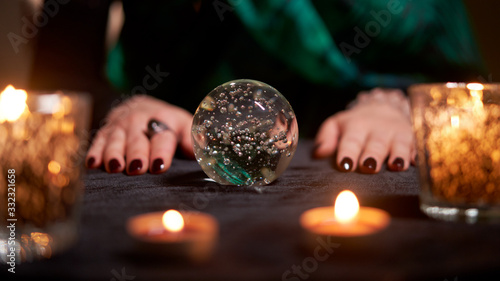 Tableau sur toile Fortuneteller divining on magic ball at table with burning candles