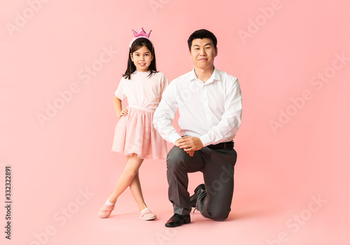 Happy Asian man and his little daughter on color background