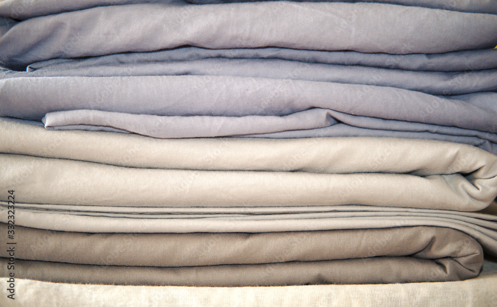 pile of bed clothes or bed linen to iron. home work concept. monochrome gradient white gray blue bed linen textiles clothing. pile of bed clothes or bed linen to iron. home work concept. monochrome gradient white gray blue bed linen textiles clothing.