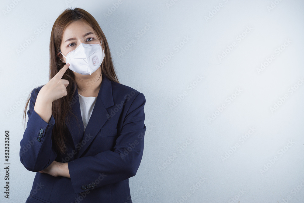 The business woman wearing protection face mask against coronavirus, PM 2.5 and cold, and her finger point on her mask. The business woman wearing protection face mask against coronavirus, PM 2.5 and cold, and her finger point on her mask.