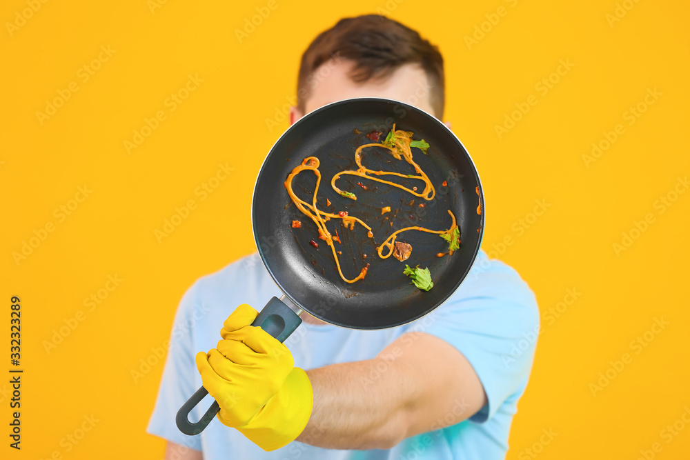 Man with dirty frying pan on color background Stock Photo | Adobe Stock