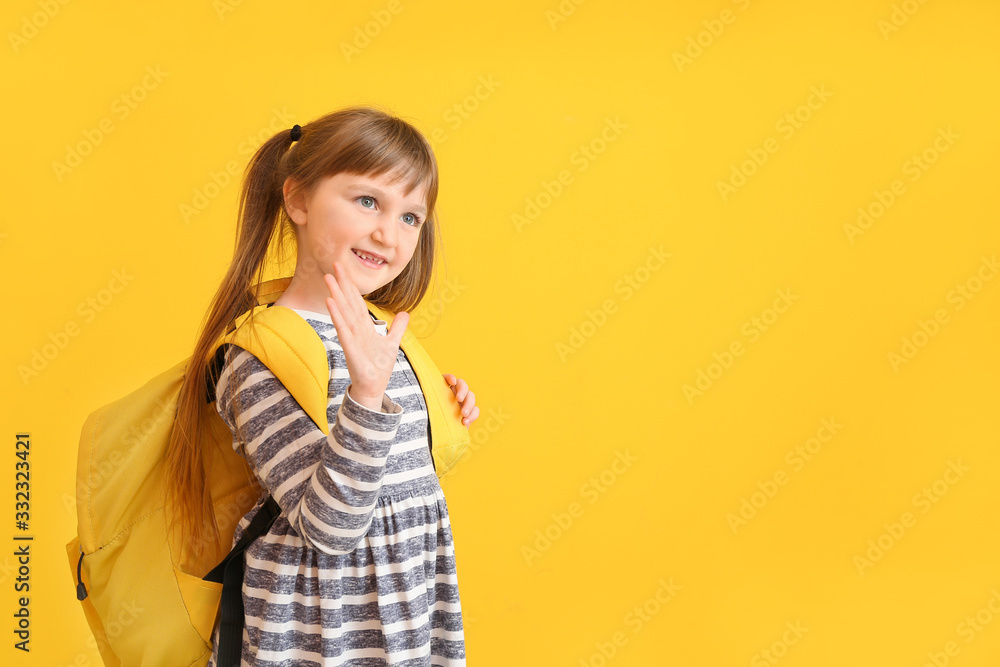 Cute little schoolgirl waving hand on color background Cute little schoolgirl waving hand on color background