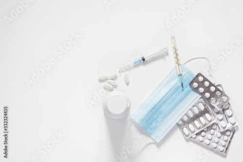 tablets and capsules for the treatment of colds and viral diseases. thermometer for measuring body temperature. a syringe for injection. the fight against viruses. white background. copy space
