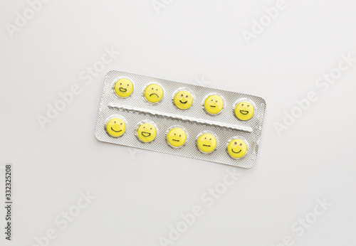 Blister pack and pills with different drawn faces on white background