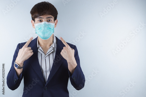 The business man wearing protection face mask against coronavirus, PM 2.5 and cold, and his finger point on his mask.