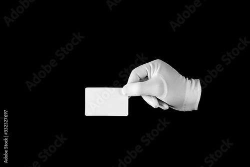 Hand in a white glove on a black background. Gestures and pantomime. Payment card.