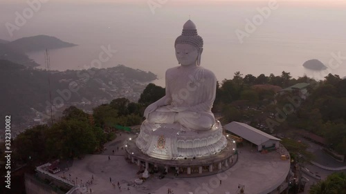 Slow aerial pivot around a huge monument of The Great Buddha of Phuket, located on top of the  Nakkerd Hill with ocean in background, on the sunset, Phuket, Thailand. photo