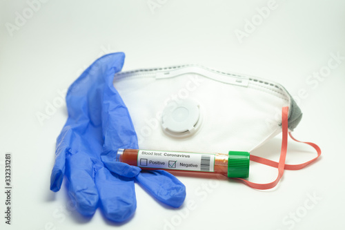 Blood test for the coronavirus. The tube is surrounded by a mask and a blue glove. The blood test is negative.