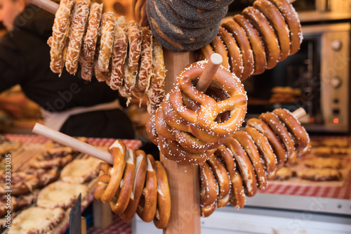 Bunch of bretzels hanged on a Christmas Market stand in Paris (Tuileries Gardens), France. Beautiful close up of this delicious typical german pastry. Covered with salt.