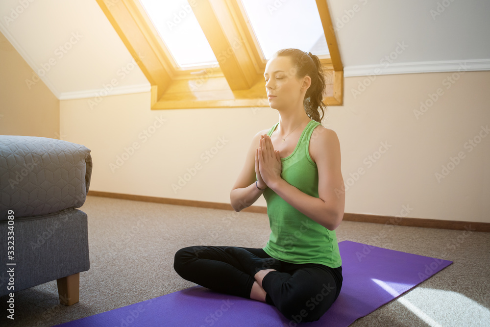 Young woman is practicing yoga at home. Padmasana / Lotus Position Young woman is practicing yoga at home. Padmasana / Lotus Position