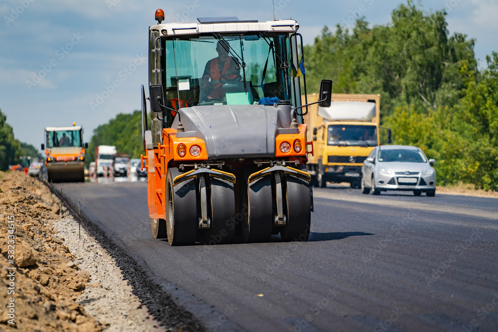 Road roller flattening new asphalt. Heavy vibration roller at work paving asphalt, road repairing. Selective focus. Road roller flattening new asphalt. Heavy vibration roller at work paving asphalt, road repairing. Selective focus.