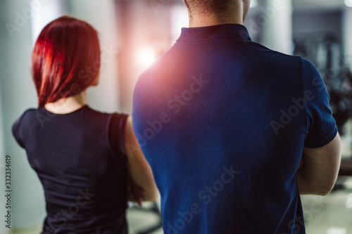 Back view of muscular sport people in half height standing crosshands over the gym background. Trainers portrait. photo