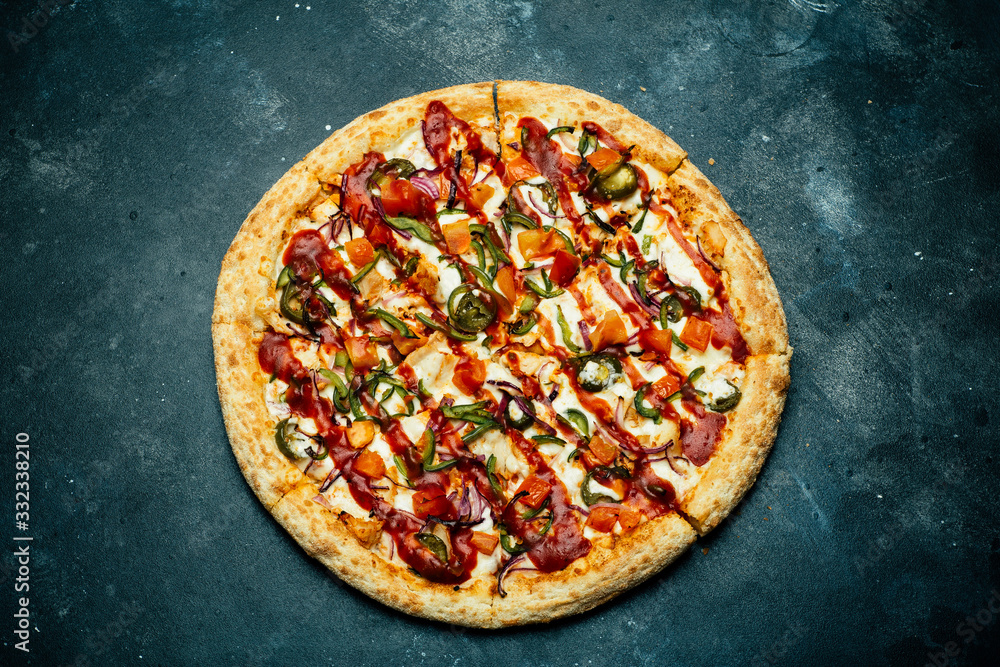 Pizza on a dark background. Classic italian pizza with tomatoes, pepper, vegetables, sauce and mazarella cheese on a dark kitchen table. Copy space