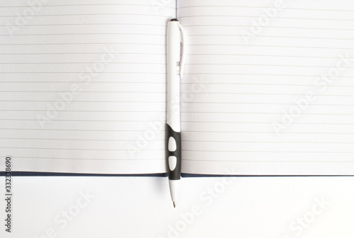 Top view of opened diary pages with the pen on white background and free space from below as template for designers.