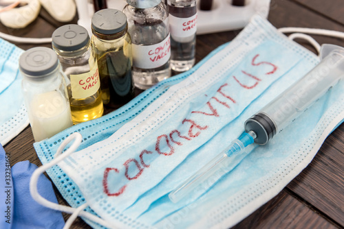 COVID-19 coronavirus ampoule with a vaccine, infected blood in the syringe, medical mask. Dangerous diseases and viruses