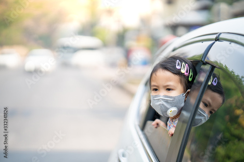 Cute little girl sitting in car wearing face mask protect filter against air pollution (pm2.5) and Covid 19