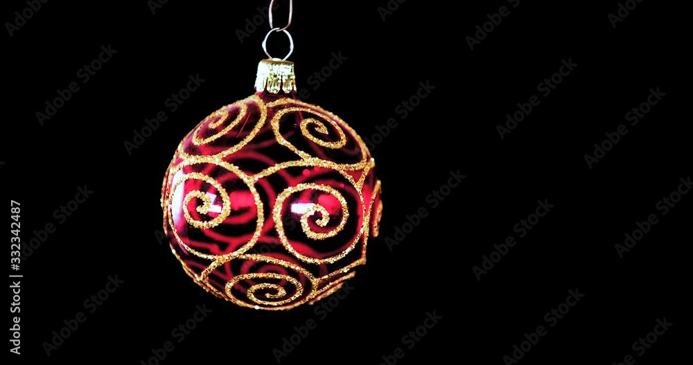 single red clear Christmas ball ornament with golden glitter stripes and black background, close up single red clear Christmas ball ornament with golden glitter stripes and black background, close up