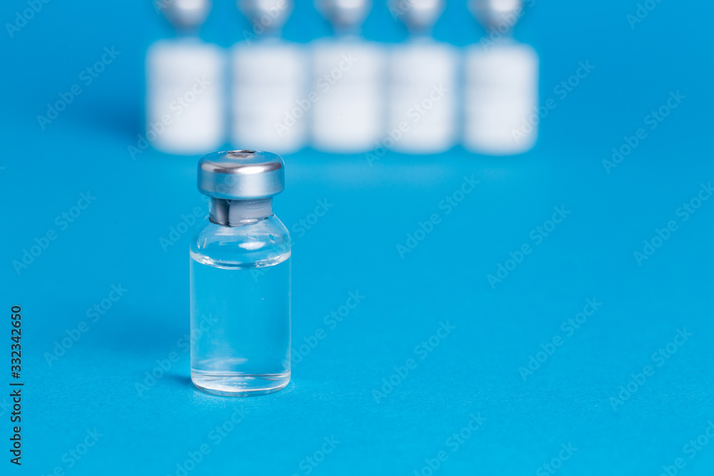 Closeup vaccine bottle on blue isolated background. Lack of coronovirus vaccine. Closeup vaccine bottle on blue isolated background. Lack of coronovirus vaccine.