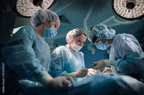 Medical team in the operating room, dark background. The theater of the operating room, an international team of professional doctors in a modern operating room are conducting an operation. Saving