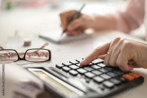 Pension calculation concept, old hands counting finances on a home calculator , close- up
