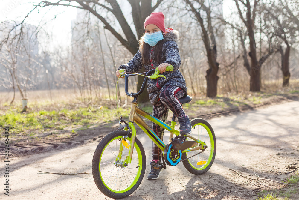 7 years old happy Little girl child ride bicycle in the park at home and wearing protection mask for protect pm2.5 and Coronavirus Covid-19 Pandemic virus symptoms.Sport exercise for health. 7 years old happy Little girl child ride bicycle in the park at home and wearing protection mask for protect pm2.5 and Coronavirus Covid-19 Pandemic virus symptoms.Sport exercise for health.