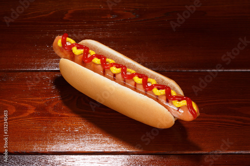 Classic hot dog with ketchup and mustard on a background of wooden boards. View from above.