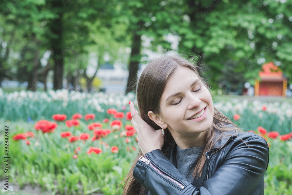 very beautiful girl portrait in a summer park on a background of red tulips very beautiful girl portrait in a summer park on a background of red tulips