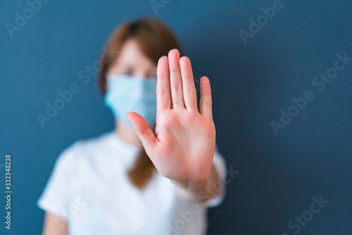 Coronavirus concept. Girl wearing mask for protection from disease and show stop hands gesture for stop corona virus outbreak. Global call to stay home.