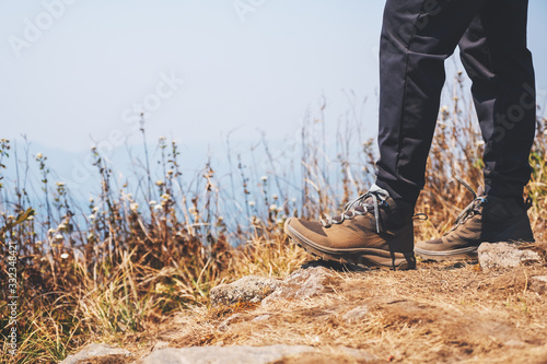 Closeup image of a woman hiking with trekking boots on the top of mountain